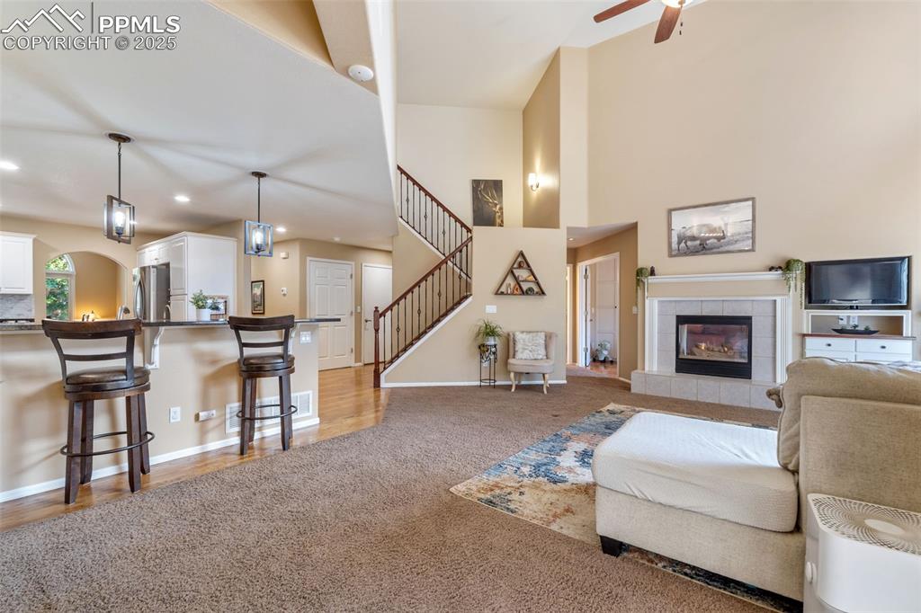 Image 13 of 50: Living area featuring light colored carpet, recessed lighting, a tiled fire