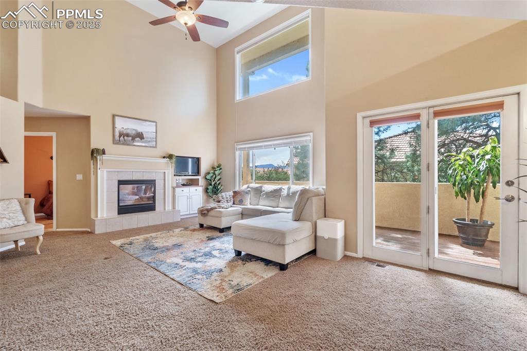 Image 14 of 50: Carpeted living room with a high ceiling, a fireplace, and ceiling fan