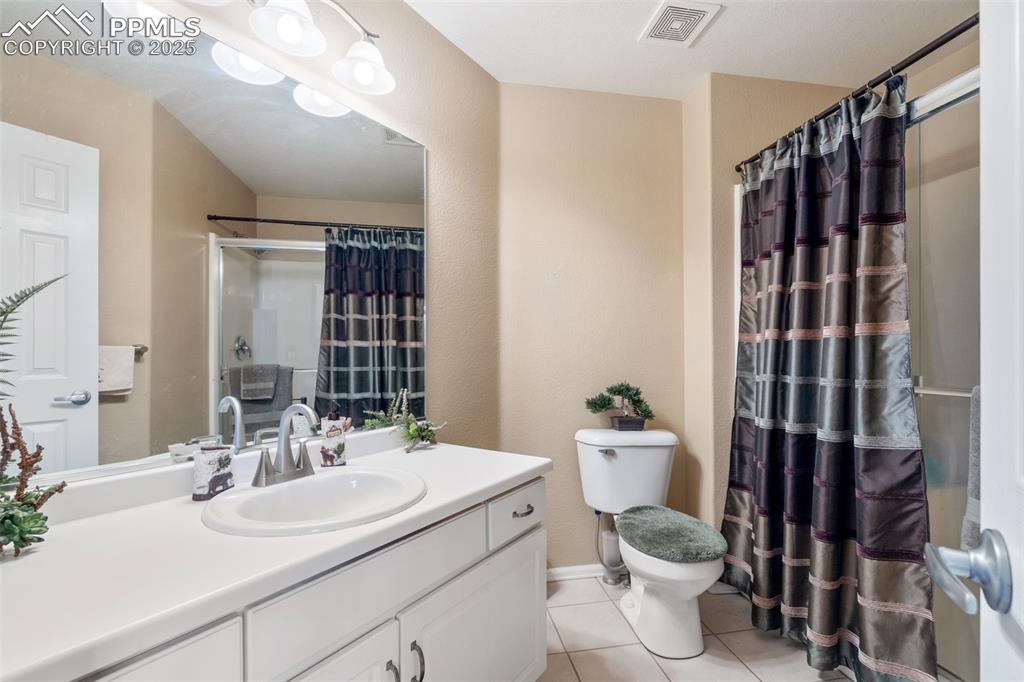 Image 19 of 50: Bathroom featuring light tile patterned floors, vanity, and a shower with s