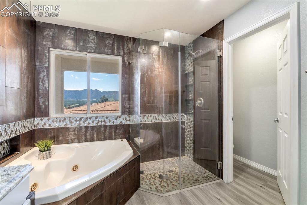 Image 27 of 50: Full bathroom with a tub with jets, a shower stall, light wood-style floori