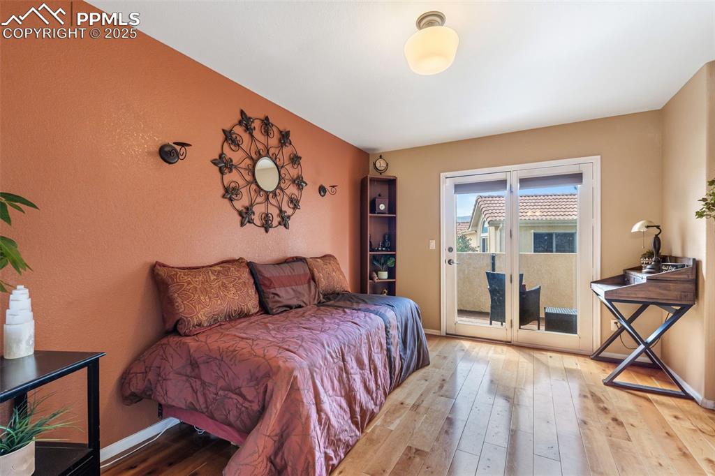 Image 30 of 50: Bedroom with hardwood / wood-style floors, a textured wall, and access to e