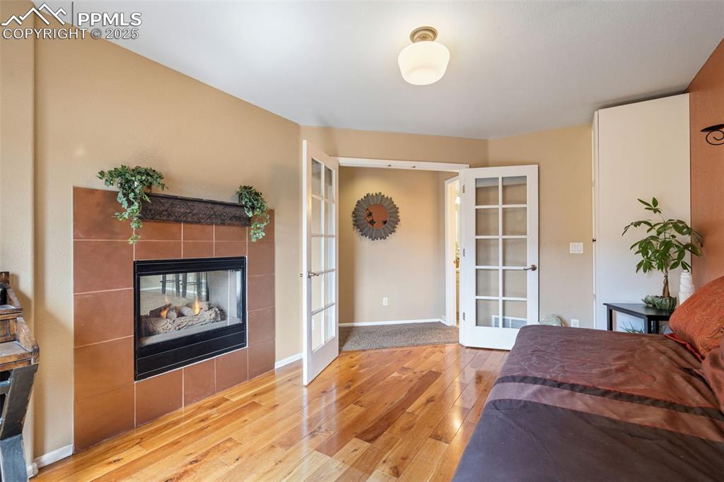 Image 31 of 50: Bedroom with french doors, a fireplace, and light wood-type flooring