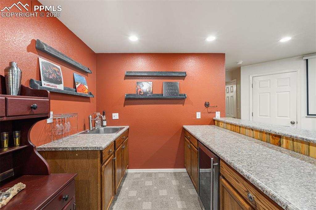 Image 38 of 50: Bar area with open shelves, wine cooler, a textured wall, recessed lighting