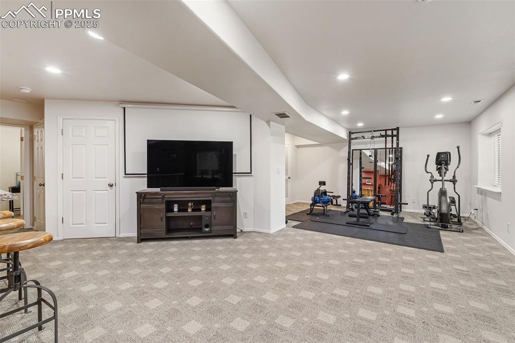 Image 40 of 50: Exercise area with recessed lighting and light colored carpet