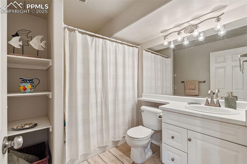 Image 41 of 50: Full bath with vanity, a shower with shower curtain, and light tile pattern