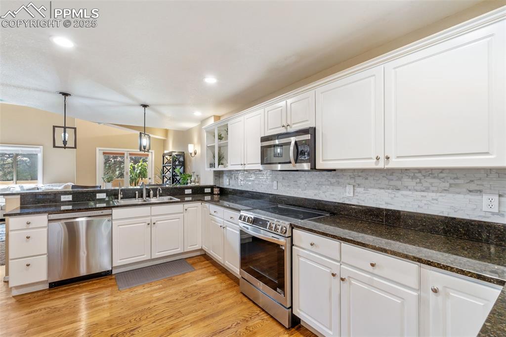 Image 7 of 50: Kitchen with stainless steel appliances, white cabinetry, light wood-style 