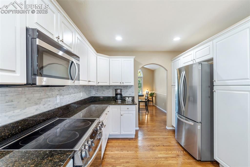 Image 9 of 50: Kitchen with appliances with stainless steel finishes, backsplash, arched w