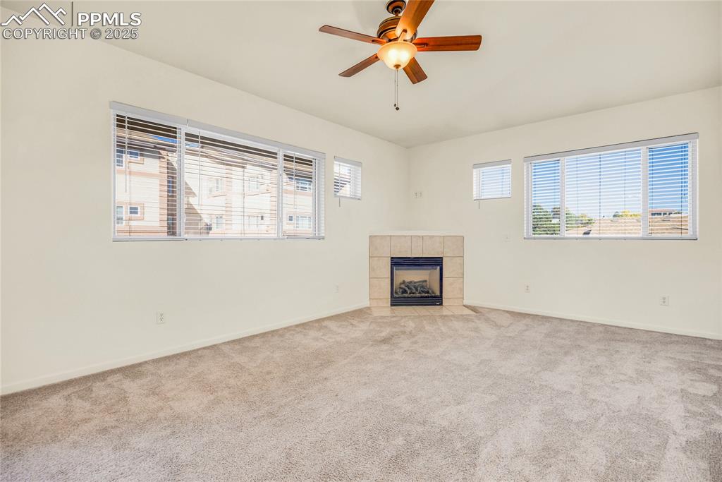 Image 12 of 37: Unfurnished living room featuring carpet, a fireplace, and a ceiling fan