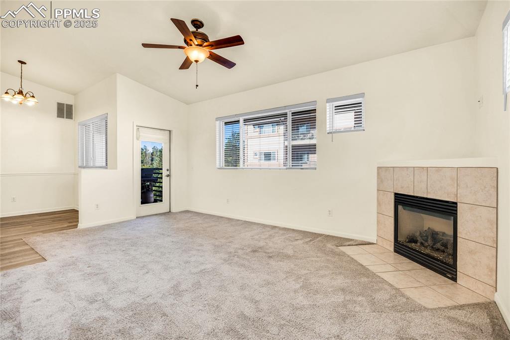 Image 13 of 37: Unfurnished living room with a tiled fireplace, light colored carpet, ceili