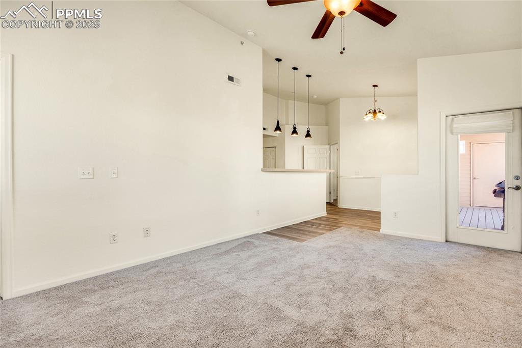 Image 15 of 37: Unfurnished living room with light carpet, ceiling fan, and a chandelier