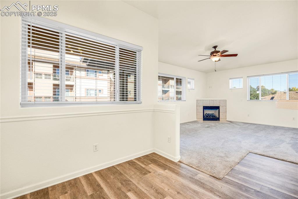 Image 17 of 37: Unfurnished living room featuring a tiled fireplace, a ceiling fan, and woo