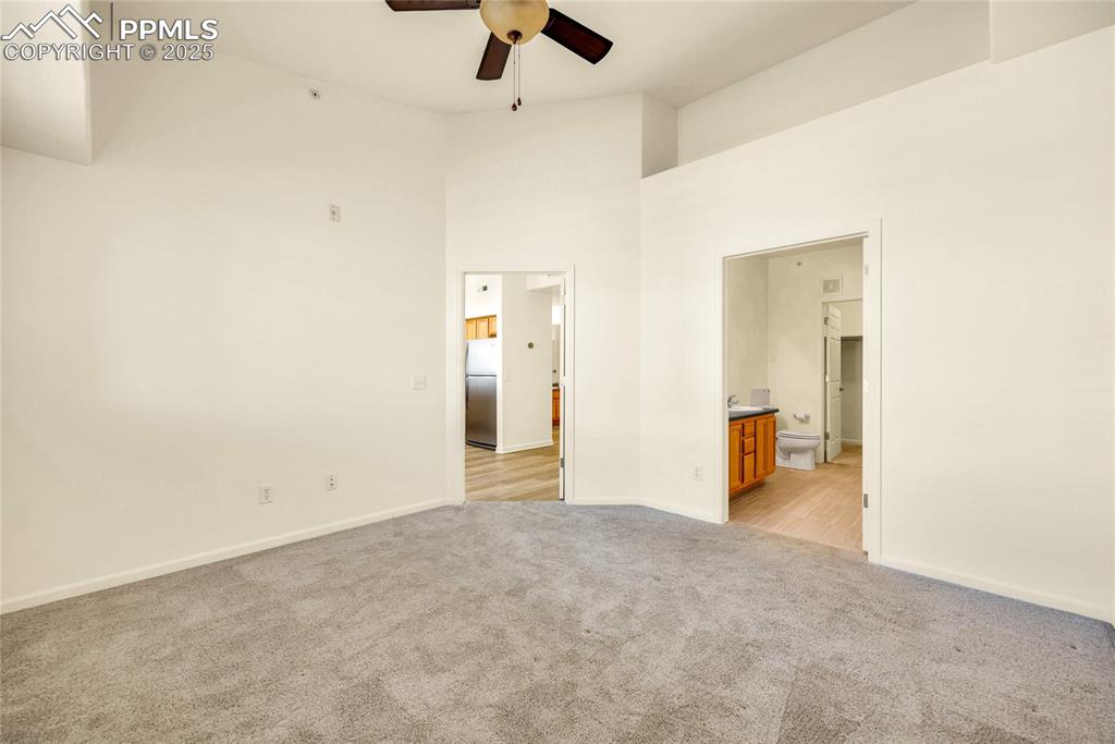 Image 20 of 37: Unfurnished bedroom with a high ceiling, freestanding refrigerator, light c