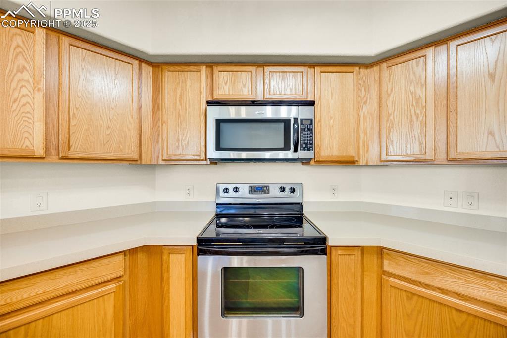 Image 6 of 37: Kitchen with stainless steel appliances and light brown cabinetry