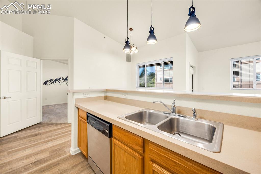 Image 8 of 37: Kitchen with light countertops, decorative light fixtures, dishwasher, ligh