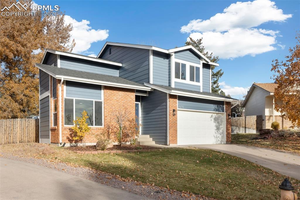 Image 35 of 36: View of front of house with a garage, brick siding, driveway, and roof with