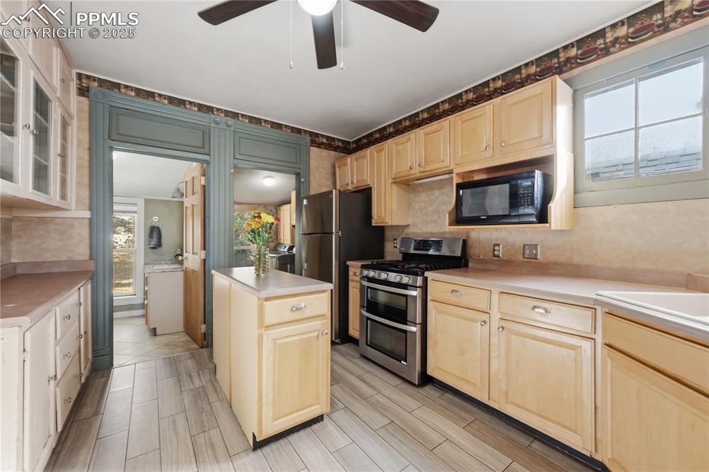 Image 14 of 36: Kitchen with appliances with stainless steel finishes, light countertops, g