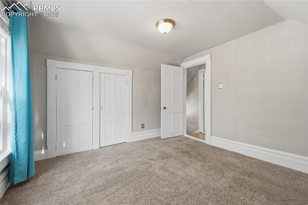 Image 20 of 36: Unfurnished bedroom featuring vaulted ceiling, multiple windows, carpet, an