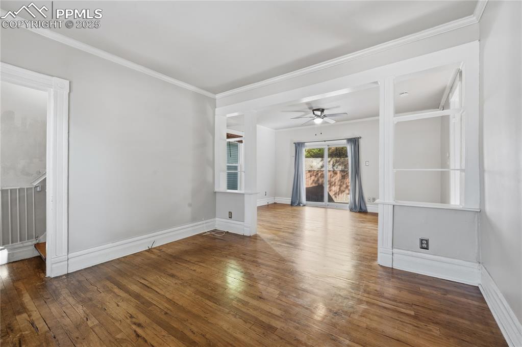 Image 6 of 36: Empty room with dark wood-style flooring, crown molding, and ceiling fan