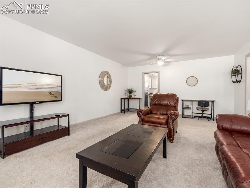 Image 12 of 18: Living room featuring light colored carpet and a ceiling fan