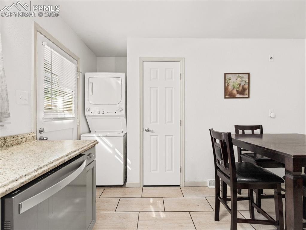 Image 16 of 18: Kitchen featuring stacked washing machine and dryer, dishwasher, and light