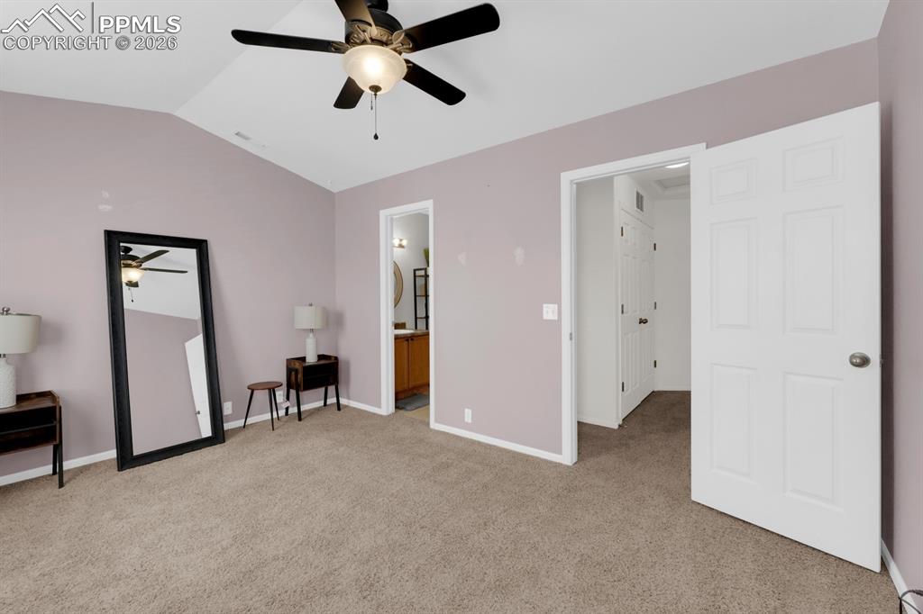 Image 10 of 15: Primary bedroom with light colored carpet, connected bathroom, and a ceilin