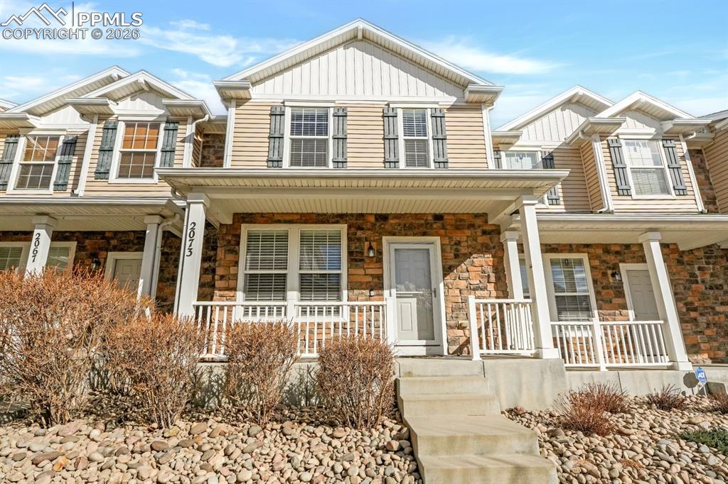 Image 2 of 15: Craftsman-style house featuring stone siding, a porch, and board and batten