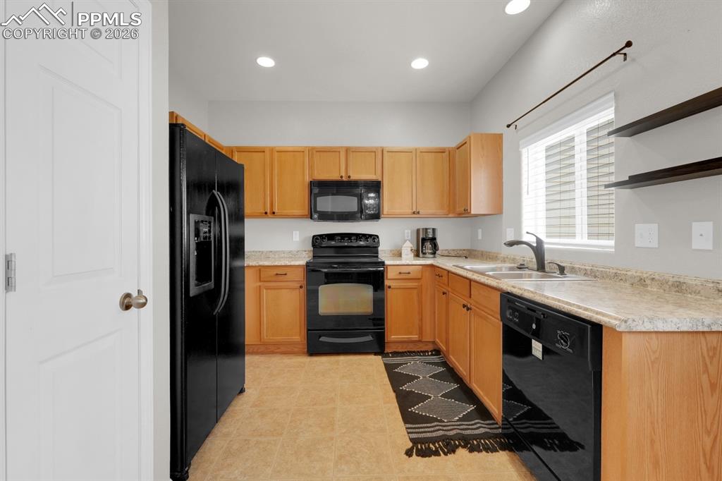 Image 5 of 15: Kitchen with black appliances, open shelves, light countertops, recessed li