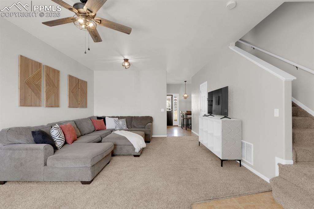 Image 6 of 15: Living area with light colored carpet and ceiling fan