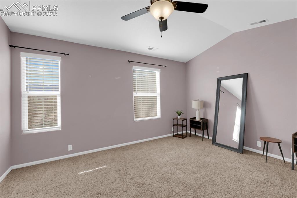 Image 9 of 15: Primary bedroom with vaulted ceiling, ceiling fan, and light colored carpet