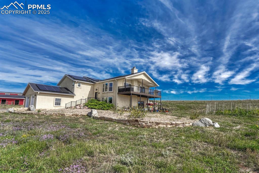 Image 17 of 50: Side of house featuring stucco siding, a chimney, and solar panels