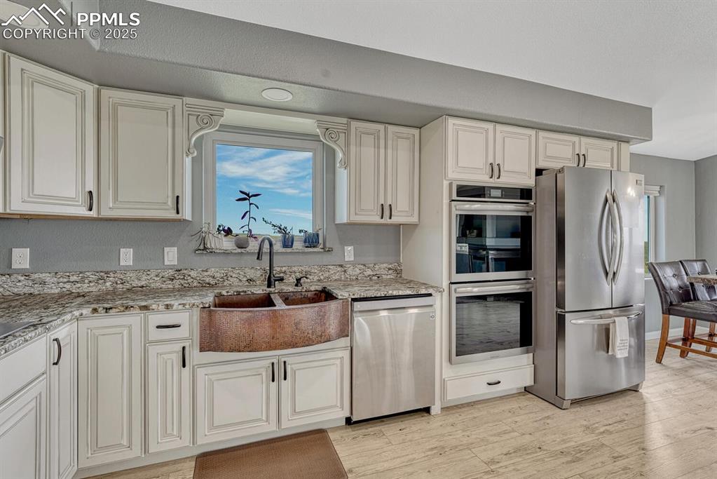 Image 21 of 50: Kitchen with stainless steel appliances, light granite counters, light wood
