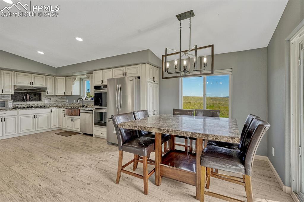 Image 23 of 50: Dining space with light wood finished floors, a chandelier, recessed lighti