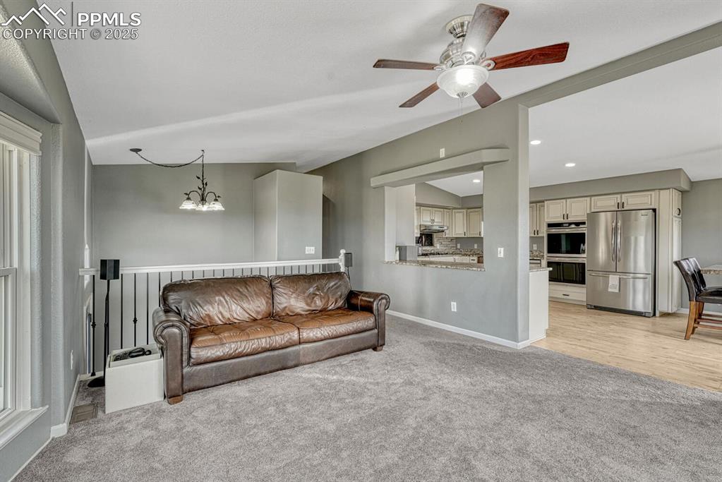 Image 36 of 50: Living area featuring light carpet, a ceiling fan, a chandelier, and recess