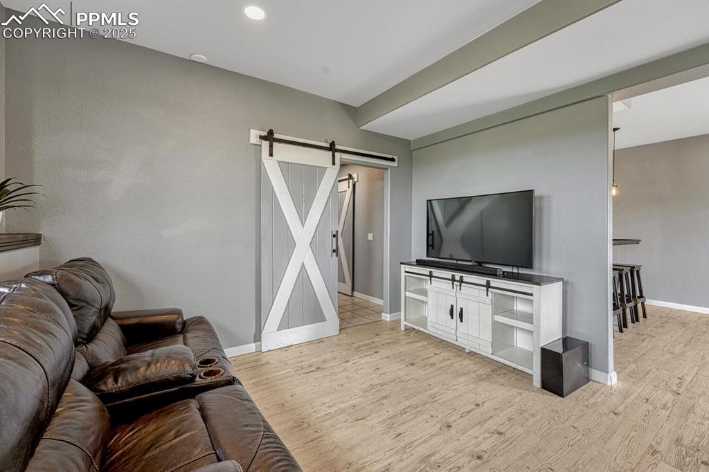 Image 38 of 50: Family room with a barn door, light wood-style floors, and recessed lightin
