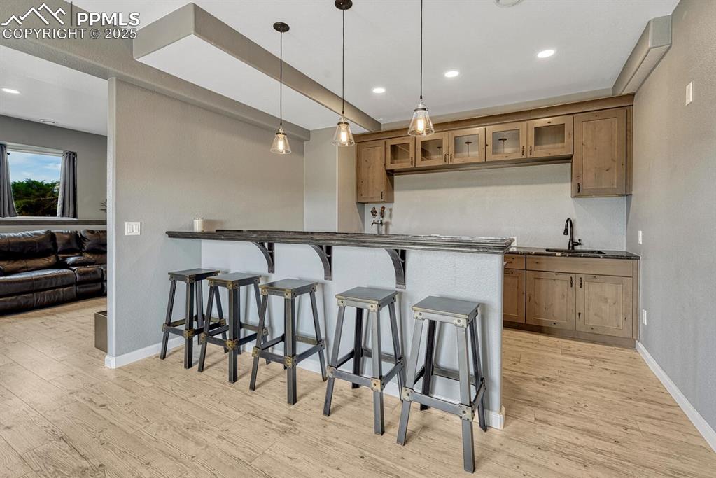 Image 40 of 50: Large Bar featuring glass insert cabinets, a breakfast bar, recessed lighti