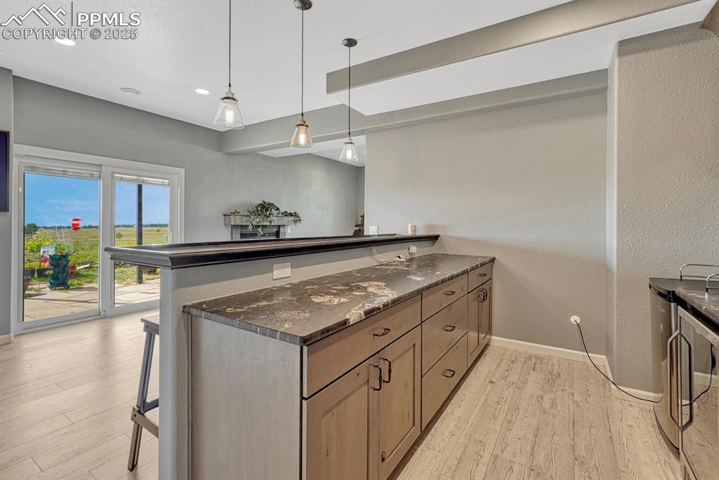 Image 42 of 50: Bar featuring pendant lighting, a peninsula, light wood-type flooring, and