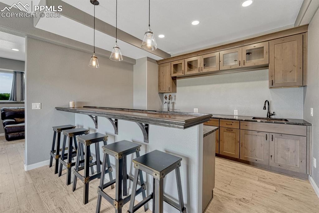 Image 43 of 50: Bar/kitchen area with glass insert cabinets, a kitchen bar, decorative ligh