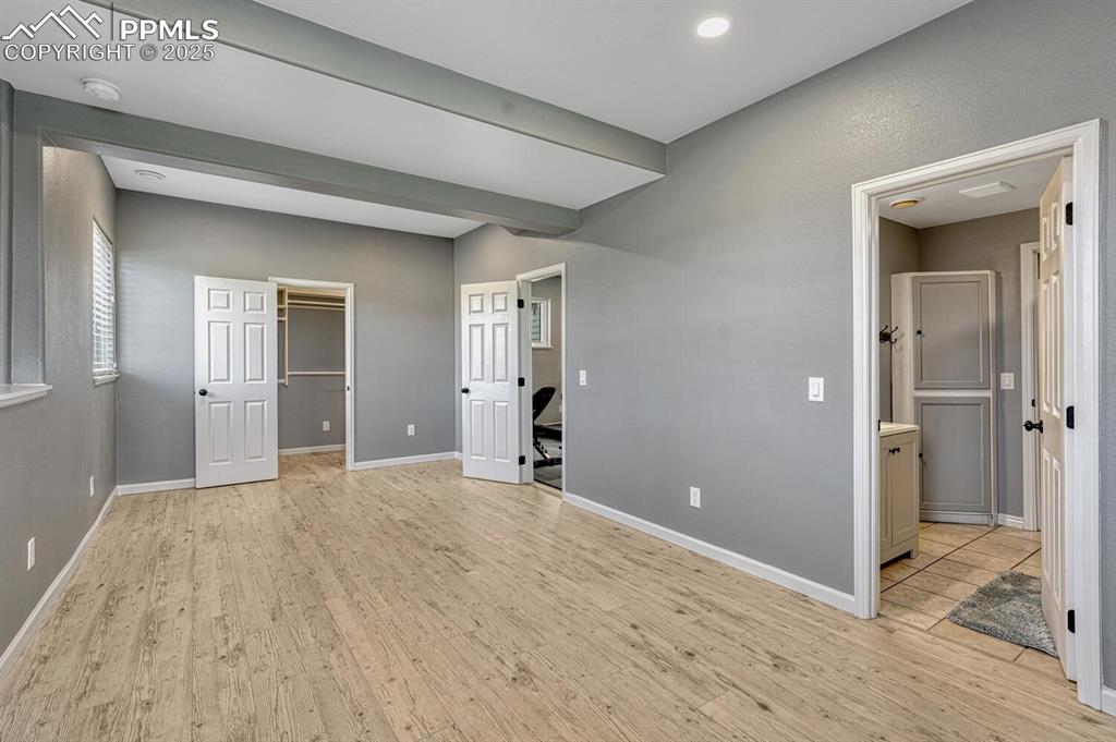 Image 46 of 50: Large bedroom featuring a walk in closet, light wood-style floors, and conn