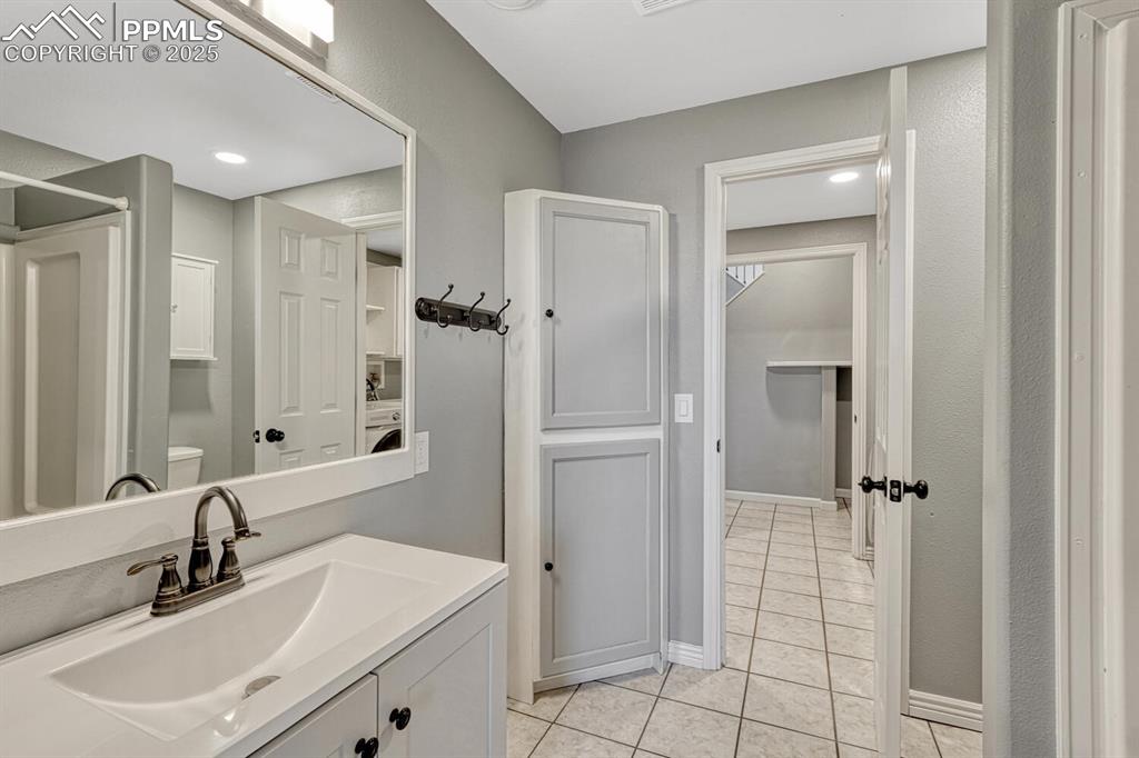 Image 48 of 50: Bathroom with light tile patterned flooring, vanity, recessed lighting