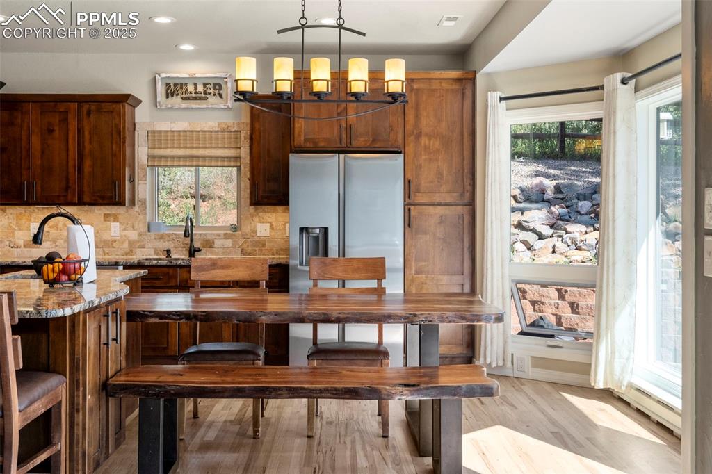 Image 10 of 46: Kitchen with light stone counters, light wood-style floors, stainless steel