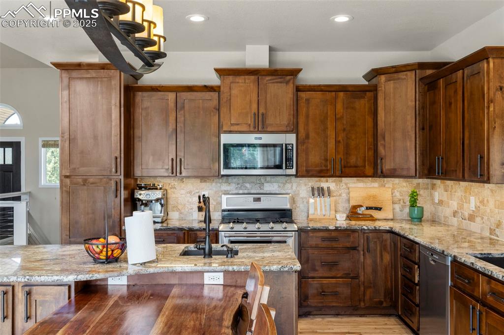 Image 11 of 46: Kitchen featuring light stone countertops, stainless steel appliances, rece