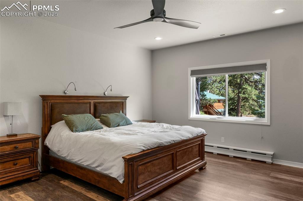 Image 16 of 46: Bedroom with a baseboard heating unit, dark wood-style flooring, a ceiling