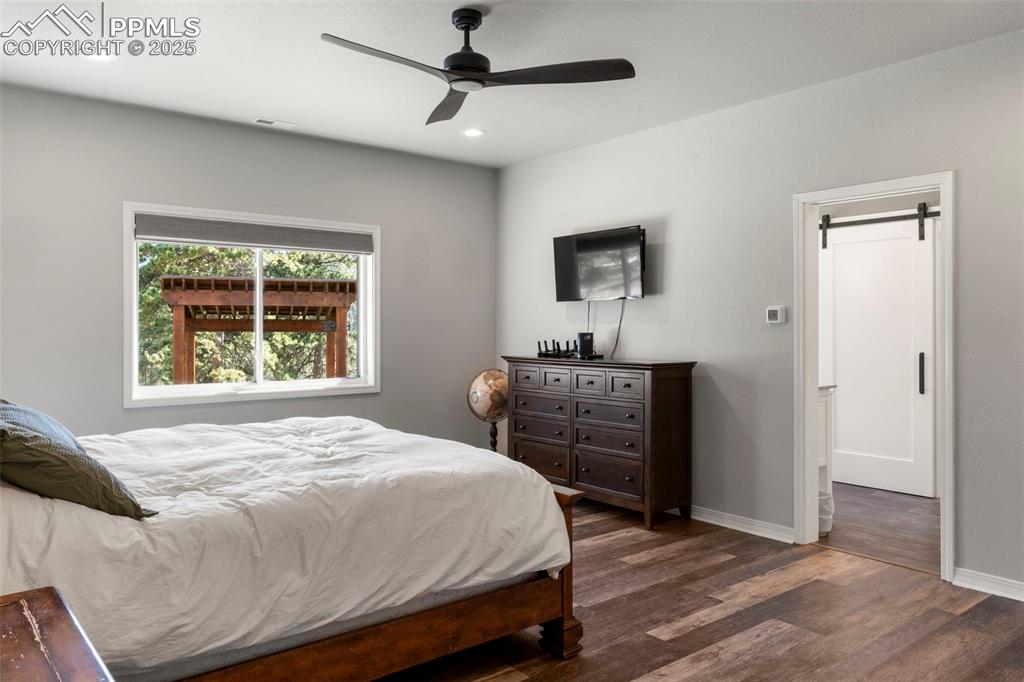 Image 17 of 46: Bedroom with dark wood finished floors, ceiling fan, and recessed lighting