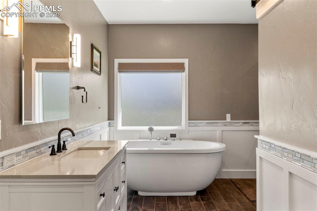 Image 19 of 46: Bathroom with vanity, a freestanding bath, a textured wall, wood finish flo