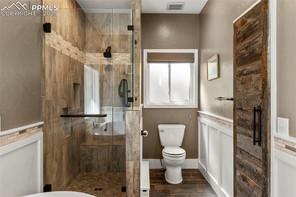 Image 20 of 46: Bathroom featuring a textured wall, a shower stall, wood tiled floors, and