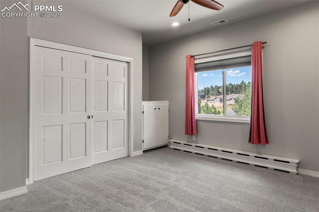 Image 22 of 46: Unfurnished bedroom featuring a baseboard radiator, light carpet, ceiling f