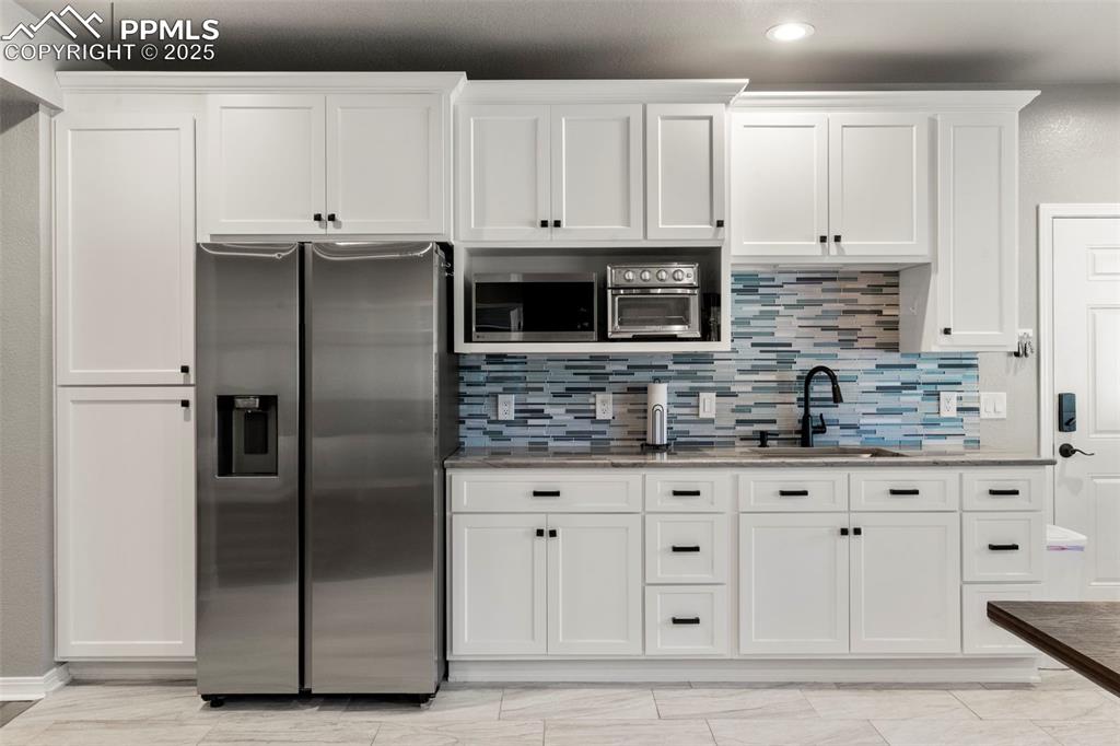 Image 26 of 46: Kitchen with white cabinets, stainless steel appliances, light stone counte