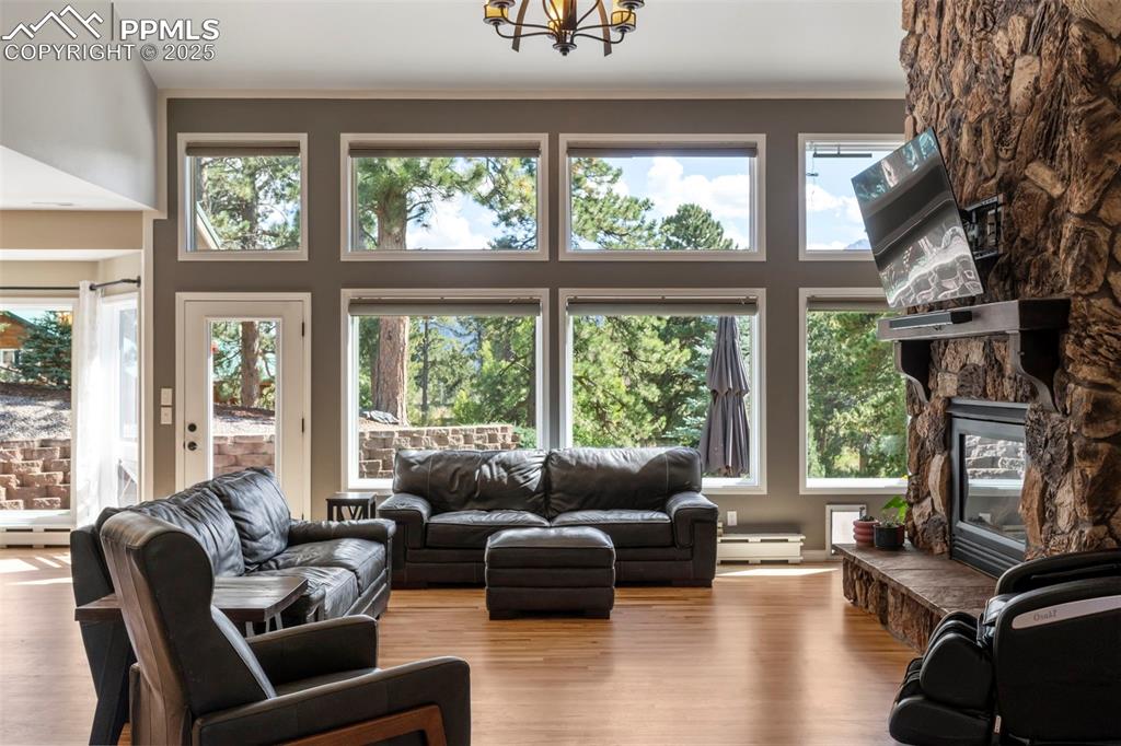 Image 3 of 46: Living area featuring wood finished floors, a fireplace, a towering ceiling