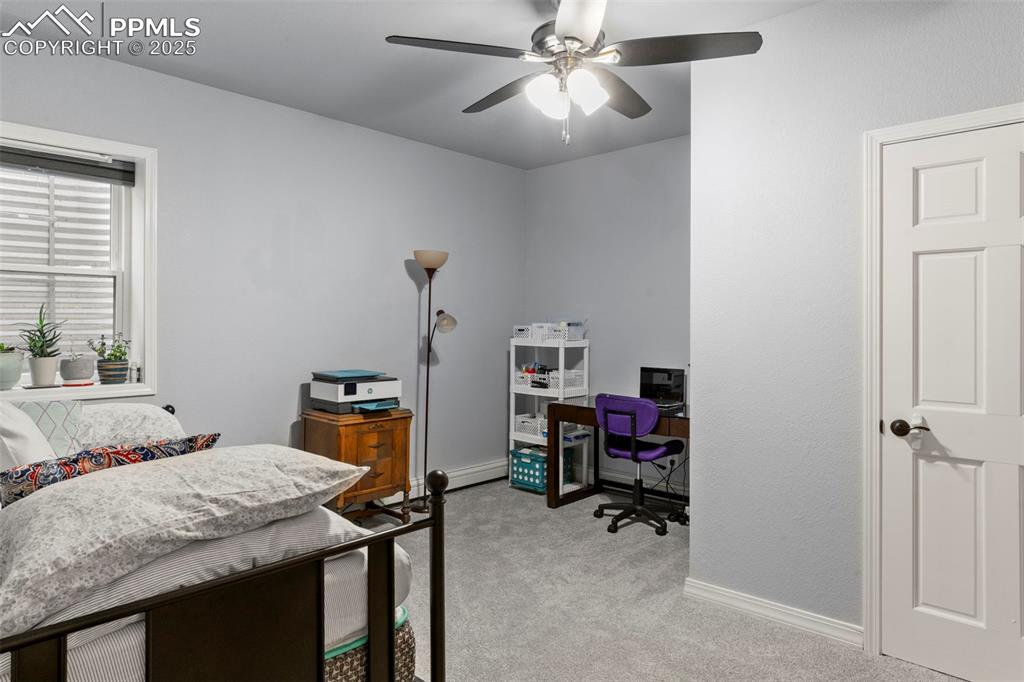 Image 30 of 46: Bedroom featuring light carpet, ceiling fan, and a desk