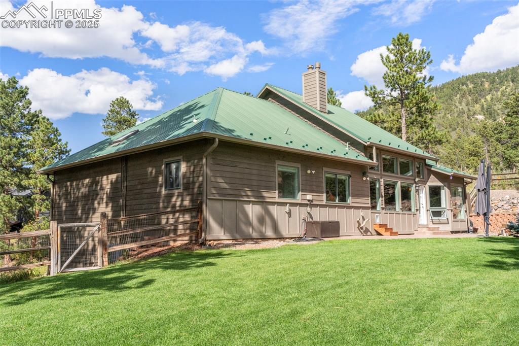 Image 37 of 46: Back of house featuring a metal roof and a chimney